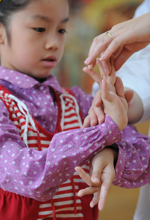 Liu Chenyan learns a gesture during a training course in her school in Nanjing, east China's Jiangsu Province, Oct. 24, 2009.