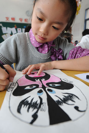 Liu Chenyan draws a Peking Opera facial mask at school in Nanjing, east China's Jiangsu Province, October 20, 2009. 