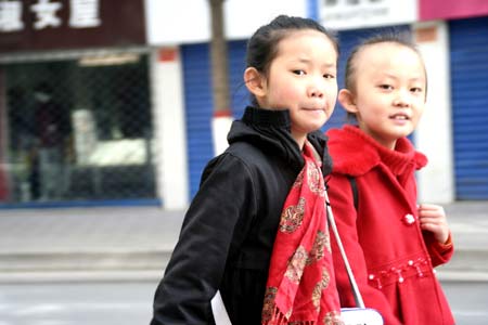 Two girls walk on street in downtown Xining looking at the camera curiously on October 31, 2009.