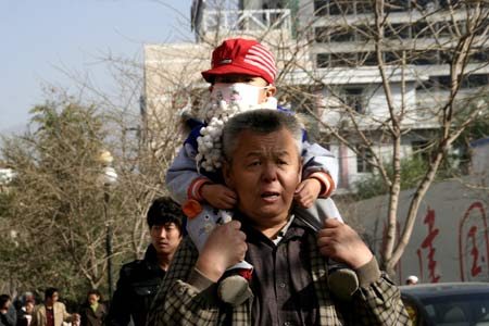 An old man with his grandson sitting on his shoulders sings while walking on street in downtown Xining on October 31, 2009. 