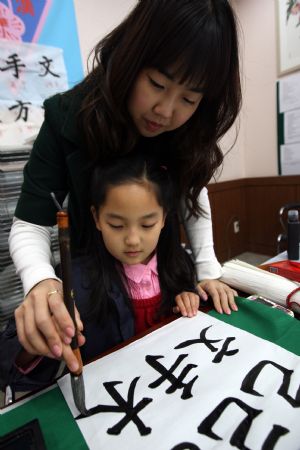 South Korean girl Lin Su Ting practises calligraphy with the help of her teacher in Seoul, capital of South Korea, November 11, 2009.