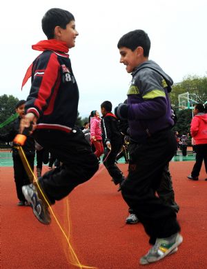 Sanlong (L) and his brother enjoy rope skipping together in Wu'ai Primary School in Yiwu City, east China's Zhejiang Province, November 13, 2009.