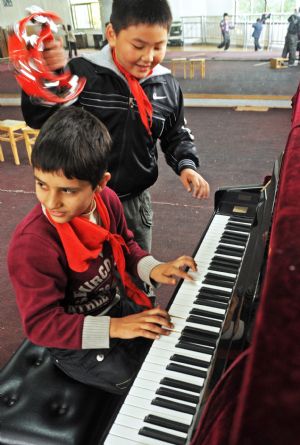 Sanlong (front) plays piano absent-mindedly in Wu'ai Primary School in Yiwu City, east China's Zhejiang Province, November 13, 2009.