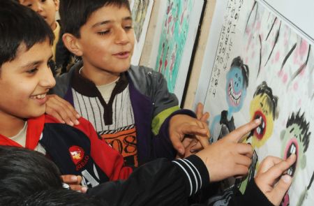 Sanlong (L1) and his brother view a piece of painting in Wu'ai Primary School in Yiwu City, east China's Zhejiang Province, November 13, 2009.