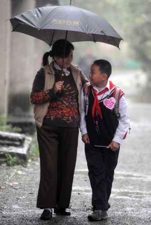 Xu Zhongzheng walk with his mother to school in rain in Dujiangyan City of Chengdu, capital of southwest China's Sichuan Province, November 11, 2009. 