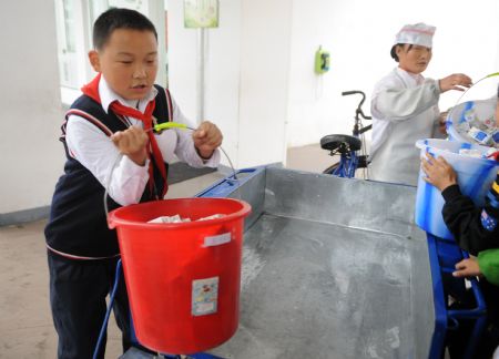 Xu Zhongzheng helps workers distribute cakes in the New Primary School of Dujiangyan City of Chengdu, capital of southwest China's Sichuan Province, November 11, 2009.