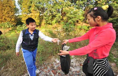 Liu Danyang picks up garbage with his friend near the river of his hometown on November 2, 2009 in Yichang, city of central China's Hubei Province.