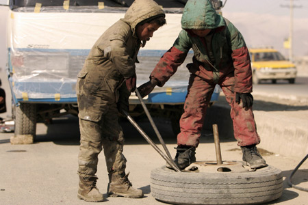 Rueid (L) and his brother Naweed repair a flat tyre at their roadside workshop in Kabul, capital of Afghanistan, on January 22, 2008.