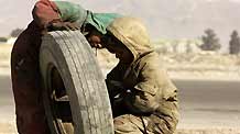 Rueid (R) and his brother Naweed repair a flat tyre at their roadside workshop in Kabul, capital of Afghanistan, on January 22, 2008.