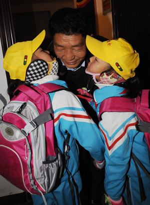 Cebae Zhoema (L) and Namgyal Zhoema, a pair of twin girls of the Tibetan ethnic group who are both pupils of Grade 5 at the No.1 Elementary School of Lhasa, kiss goodbye with their father before they go to school in Lhasa, southwest China's Tibet Autonomous Region, November 20, 2009. 