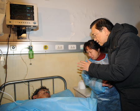 Chinese Vice Premier Zhang Dejiang (1st R) visits an injured miner at a hospital in Hegang City, northeast China's Heilongjiang Province, on November 21, 2009.