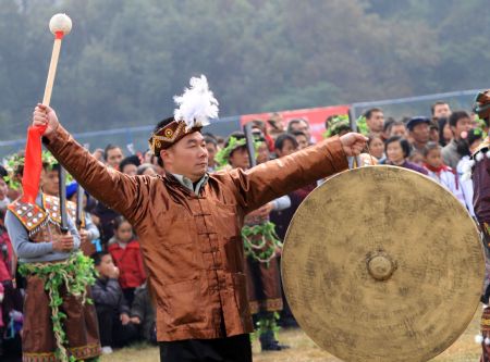 A man beats the gong to pray for good luck and bumper harvest during the Lusheng and Horse Fight Festival held in the Sports Park in Rongshui Miao Autonomous County, southwest China's Guangxi Zhuang Autonomous Region, November 21, 2009.