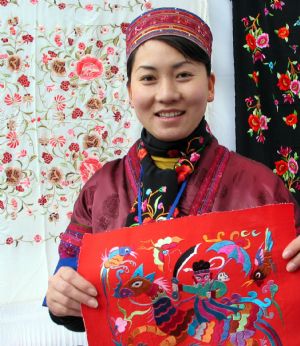 A girl of Miao ethnic group shows handmade embroideries at the tourist products fair held in Guiyang, capital of southwest China&apos;s Guizhou Province, November 27, 2009.