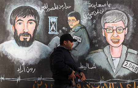 A Hamas policeman walks past a mural depicting the captured Israeli soldier Gilad Shalit (C), who has been held by Hamas-linked militants in Gaza since 2006, in Gaza City, November 2, 2009. 