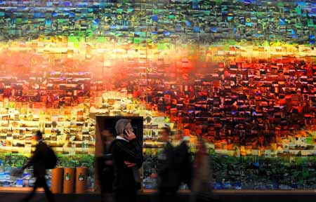 People walk past a mosaic wall warning the climate change at Bella Center in Copenhagen, capital of Denmark, December 7, 2009. The 15th United Nations Climate Change Conference (COP15) opens at Bella Center on December 7, and it will last to 18th.