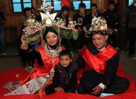 Li Zhengqian(R) and Pan Libin(L) hold wedding with their five-year-old son Pan Baohong, in Tonglian Village of Rongshui Miao Autonomous County, southwest China's Guangxi Zhuang Autonomous Region, December 6, 2009.