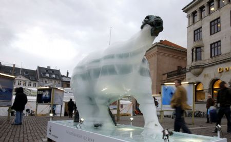 People pass by an ice sculpture of a polar bear as it melts to reveal a bronze skeleton in Copenhagen December 8, 2009.