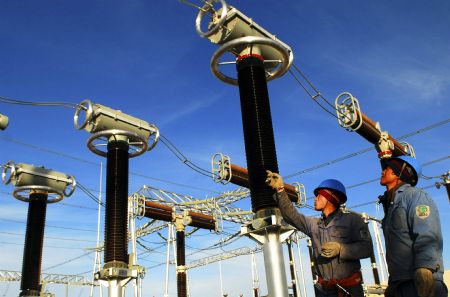 Two electricians conduct on spot technical inspection and debugging to the apparatus of the 330 kilovoltage booster substation, at the Jiuquan Dongfeng Electricity Generation Field, in Guazhou County of Jiuquan City, northwest China's Gansu Province, December 8, 2009. 