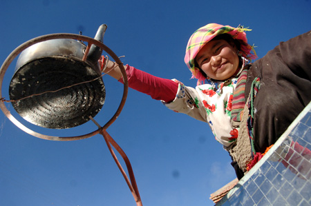 A villager uses solar energy to cook in a village in Tibetan Autonomous Prefecture of Huangnan in northwest China&apos;s Qinghai Province, December 3, 2009. 