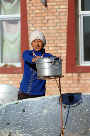 A Tibetan woman uses solar energy to cook in a village in Tibetan Autonomous Prefecture of Huangnan in northwest China&apos;s Qinghai Province, December 3, 2009.