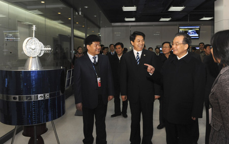 Chinese Premier Wen Jiabao (2nd R) looks at a meteorological satellite model of FY-series at the National Satellite Meteorological Center while visiting China Meteorological Administration in Beijing, capital of China, December 11, 2009.