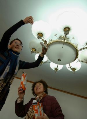 Citizens change energy-saving light bulbs at home in Jinzhou City, northeast China's Liaoning Province, December 12, 2009. Environmental protection volunteers in the Xitaiping Community of Jinzhou City launch activities among the residents of the community to recycle refuse, save water and energy in their daily life to promote low-carbon lifestyle.