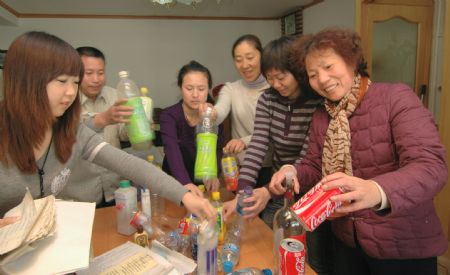Environmental protection volunteers collect plastic bottles for recycling at a local citizen's house in Jinzhou City, northeast China's Liaoning Province, December 12, 2009.