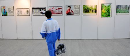 A student views the photos during a photo exhibition of the 2009 Universal Children's Day in Haikou, capital of south China's Hainan Province, December 17, 2009.