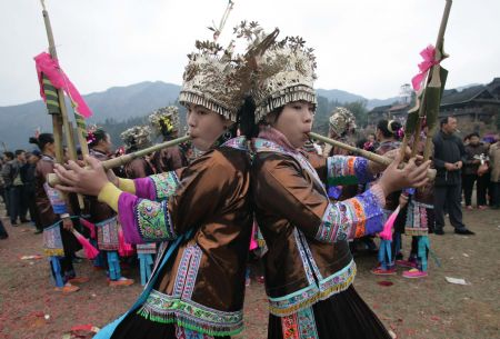 Two girls of the Miao ethnic group play the reed flute together in Rongshui Miao Autonomous County of southwest China's Guangxi Zhuang Autonomous Region, Dec. 17, 2009, as the Miao people welcome their new year according to their own calendar.(Xinhua/Wang Zhongkang)