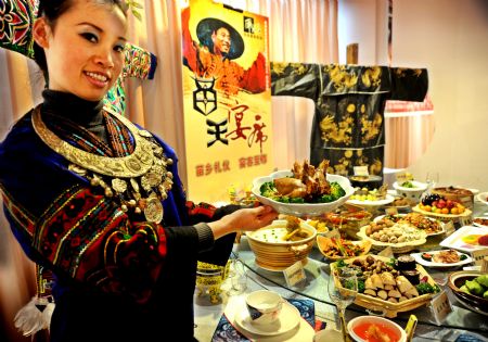 A lady in costume of Miao ethnic group shows typical Miao cuisine at the 2009 Guiyang Contest of Cuisine for Tourism in Guiyang, southwest China's Guizhou Province, Dec. 18, 2009.(Xinhua/Liu Hui)
