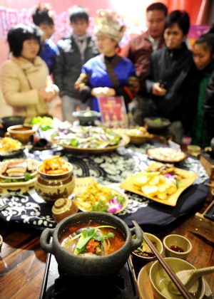 Visitors listen to the introduction of the cuisine at the 2009 Guiyang Contest of Cuisine for Tourism in Guiyang, southwest China's Guizhou Province, Dec. 18, 2009.(Xinhua/Liu Hui)