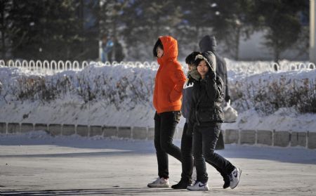 People walk in a snow-covered street in Yakeshi, north China's Inner Mongolia Autonomous Region, December 19, 2009. A cold snap coming from Siberia swept easter part of Inner Mongolia on Friday and Saturday. The cold snap brought sharp drop of temperatures in the autonomous region where the lowest temperatures fell to about minus 30 degrees Celsius. 