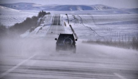 A car runs along a snow-covered road in north China's Inner Mongolia Autonomous Region, December 19, 2009. A cold snap coming from Siberia swept easter part of Inner Mongolia on Friday and Saturday. The cold snap brought sharp drop of temperatures in the autonomous region where the lowest temperatures fell to about minus 30 degrees Celsius. 