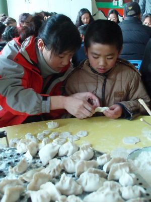 A volunteer teaches disabled children to make dumplings, or jiaozi in Chinese, at Xi'an Xinxin Kindergarten in Xi'an, capital of northwest China's Shaanxi Province, December 19, 2009. With the advent of winter solstice, over 30 volunteers came to Xi'an Xinxin Kindergarten on Saturday and made dumplings with the disabled children there.