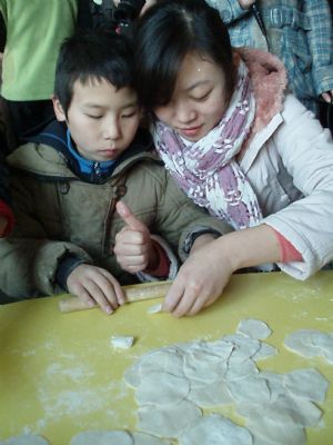 A volunteer teaches disabled children to make dumplings, or jiaozi in Chinese, at Xi'an Xinxin Kindergarten in Xi'an, capital of northwest China's Shaanxi Province, December 19, 2009. With the advent of winter solstice, over 30 volunteers came to Xi'an Xinxin Kindergarten on Saturday and made dumplings with the disabled children there.