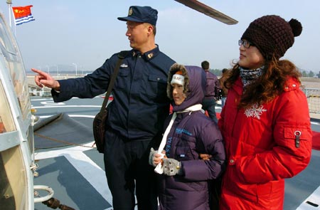 A Chinese navy soldier gives an introduction on the 'Zhoushan' Warship to his wife and daughter during their visit to the warship in a military port in Zhoushan, Zhejiang Province, December 20, 2009.