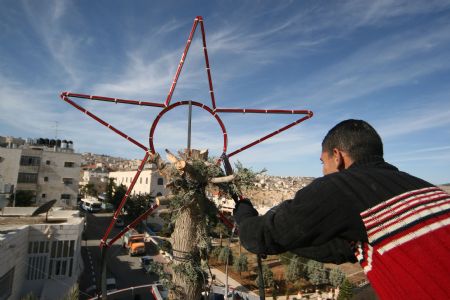 A Palestinian Municipal worker decorates the main Christmas tree in the West Bank city of Beit Sahour near Bethlehem on December 19, 2009, 4 days before the Christmas. Scores of Christian pilgrims are preparing to gather in the traditional birthplace of Jesus Christ at the West Bank to celebrate Christmas. 