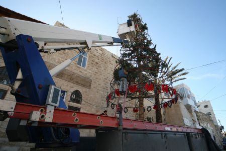Palestinian Municipal workers decorate the main Christmas tree in the West Bank city of Beit Sahour near Bethlehem on December 19, 2009, four days before the Christmas. Scores of Christian pilgrims are preparing to gather in the traditional birthplace of Jesus Christ at the West Bank to celebrate Christmas.