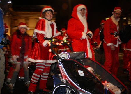 A couple of roller skaters dressed as Santa Clause push a baby carriage as they skate along the streets during the Santa Skate in London, capital of Britain, on December 19, 2009. 