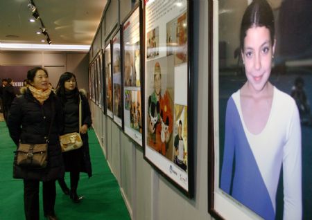 People look at pictures during the 2009 Universal Children's Day photo exhibition in Hohhot, capital city of north China's Inner Mongolia Autonomous Region, December 22, 2009.