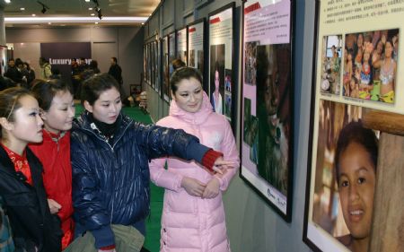 People look at pictures during the 2009 Universal Children's Day photo exhibition in Hohhot, capital city of north China's Inner Mongolia Autonomous Region, December 22, 2009.