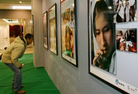 A man looks at pictures during the 2009 Universal Children's Day photo exhibition in Hohhot, capital city of north China's Inner Mongolia Autonomous Region, December 22, 2009.