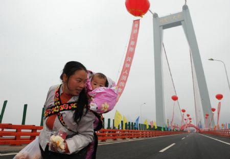 A woman carrying her child on her back walks on the Balinghe Bridge in Guanling County, southwest China's Guizhou Province, December 23, 2009. 