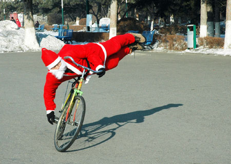 Zhou Changchun dressed as Santa Claus performs bike stunt in Changchun, capital of northeast China's Jilin Province, December 23, 2009. 