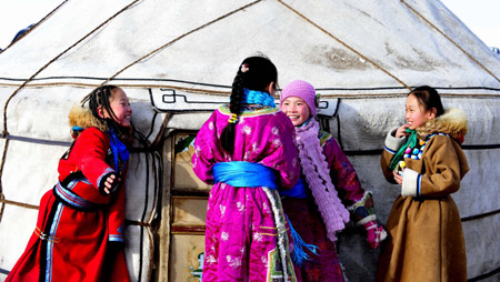 Girls of Mongolian ethnic group laugh in front of a Monglian yurt in Xi Ujimqin Qi, north China's Inner Mongolia Autonomous Region, on December 28, 2009.