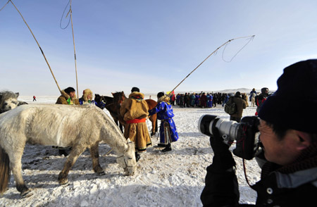 A photographer takes photos of the ice and snow carnival in Xi Ujimqin Qi, north China's Inner Mongolia Autonomous Region, on December 28, 2009.
