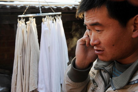 Tao Huajiang talks on phone with a donator at Magezhuang village in Pingdu City, east China's Shandong Province January 6, 2010.