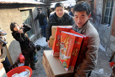 Tao Huajiang (R) carries donations at Magezhuang village in Pingdu City, east China's Shandong Province January 6, 2010. 