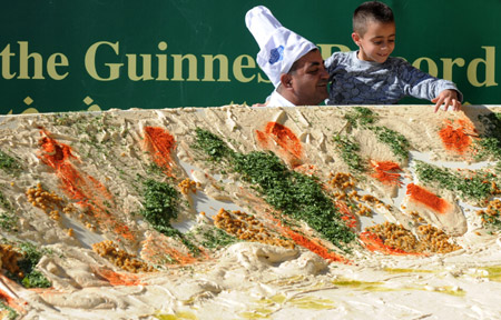 A chef helps a boy to taste the world's biggest hummus in Abu Gosh, an Arab village about 10 kilometers west of Jerusalem, on January 8, 2010.