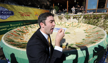 A representative of the Guinness World Records tastes the world's biggest hummus in Abu Gosh, an Arab village about 10 kilometers west of Jerusalem, on January 8, 2010.